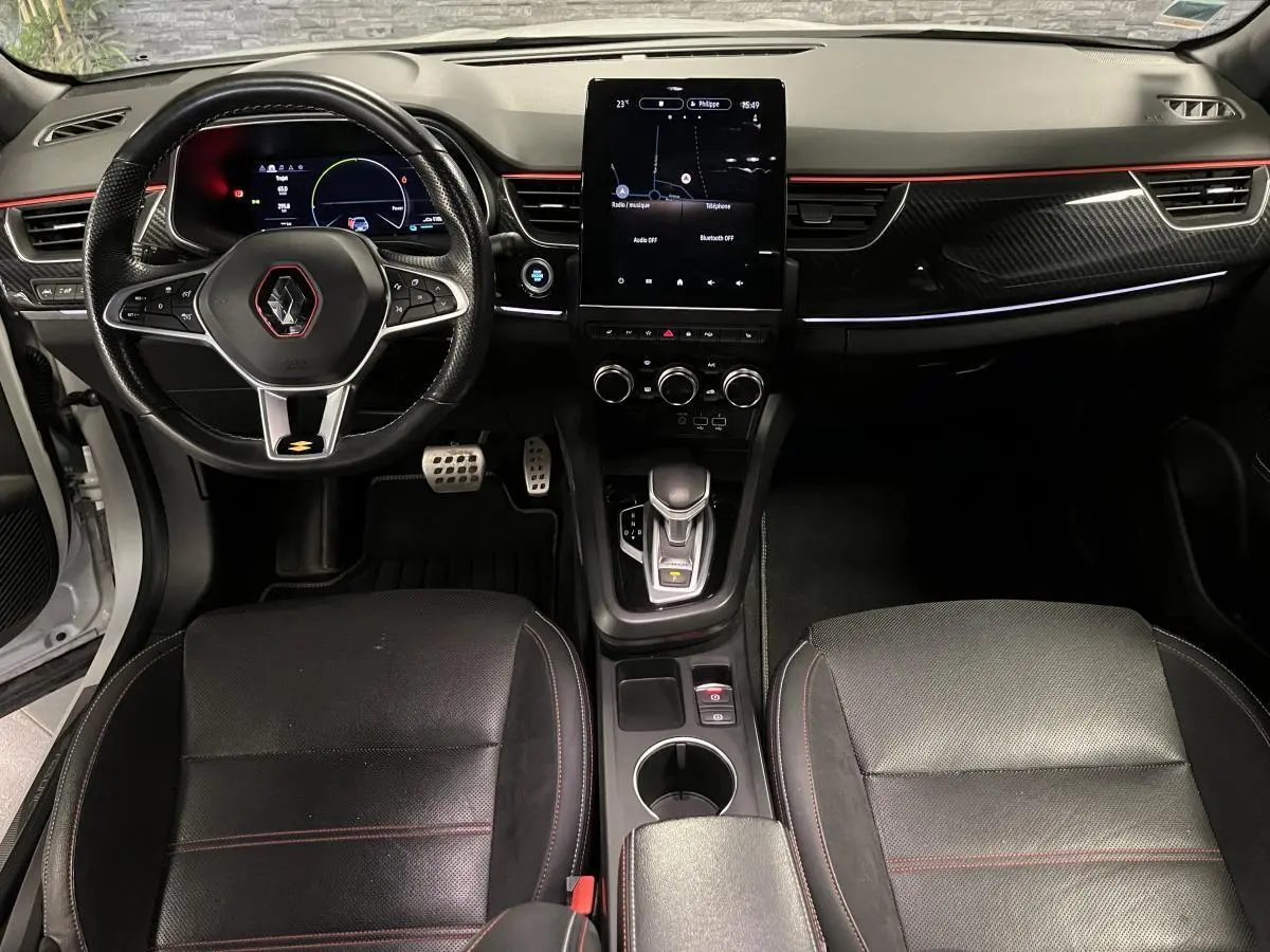 Intérieur avant du Renault Arkana 1.6 E-Tech Hybride 2022 avec volant sport, écran tactile vertical et surpiqûres rouges R.S. Line.