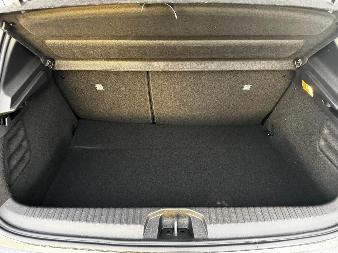 Coffre ouvert de Renault Clio V hybride gris schiste, vue intérieure montrant le volume de chargement vide.