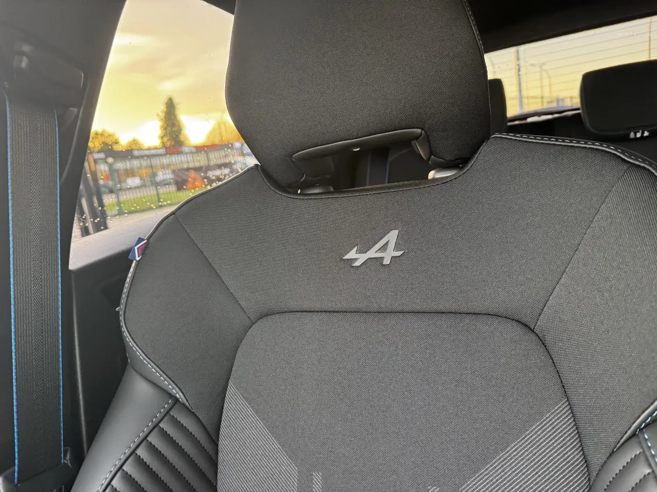 Gros plan sur le siège avant noir avec logo Alpine et surpiqûres bleues dans une Renault Clio Gris Schiste Métal.