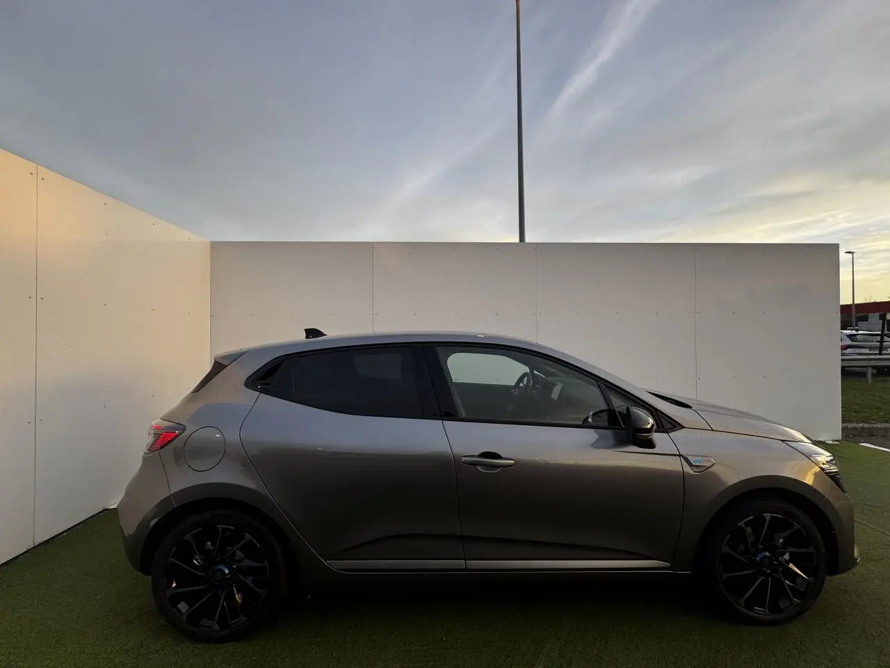 Profil côté gauche de la Renault Clio V hybride gris schiste métal avec jantes noires et vitre teintée.