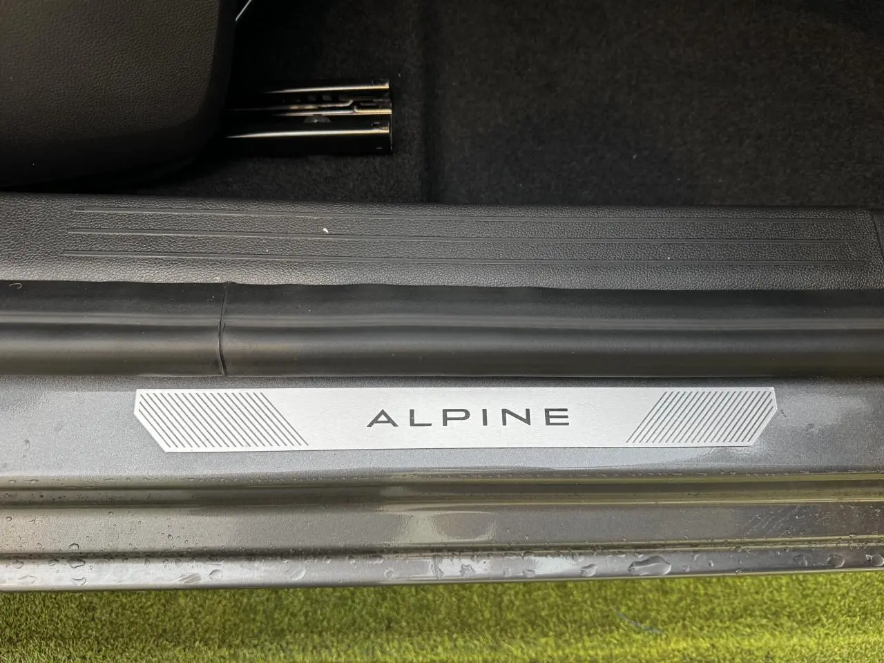 Gros plan sur la plaque de seuil de porte "ALPINE" du Renault Clio gris schiste, côté intérieur au sol.