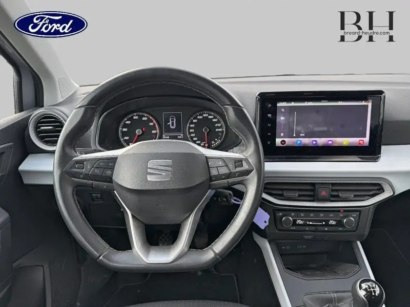 Vue intérieure centrée sur le volant cuir et le tableau de bord numérique d'une SEAT Arona gris urbain métal 2022.