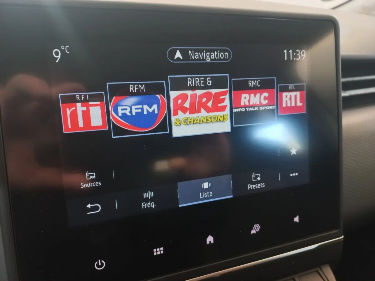 Écran tactile central de la Renault Clio Business blanc, affichant les stations radio FM avec température extérieure à 9°C.