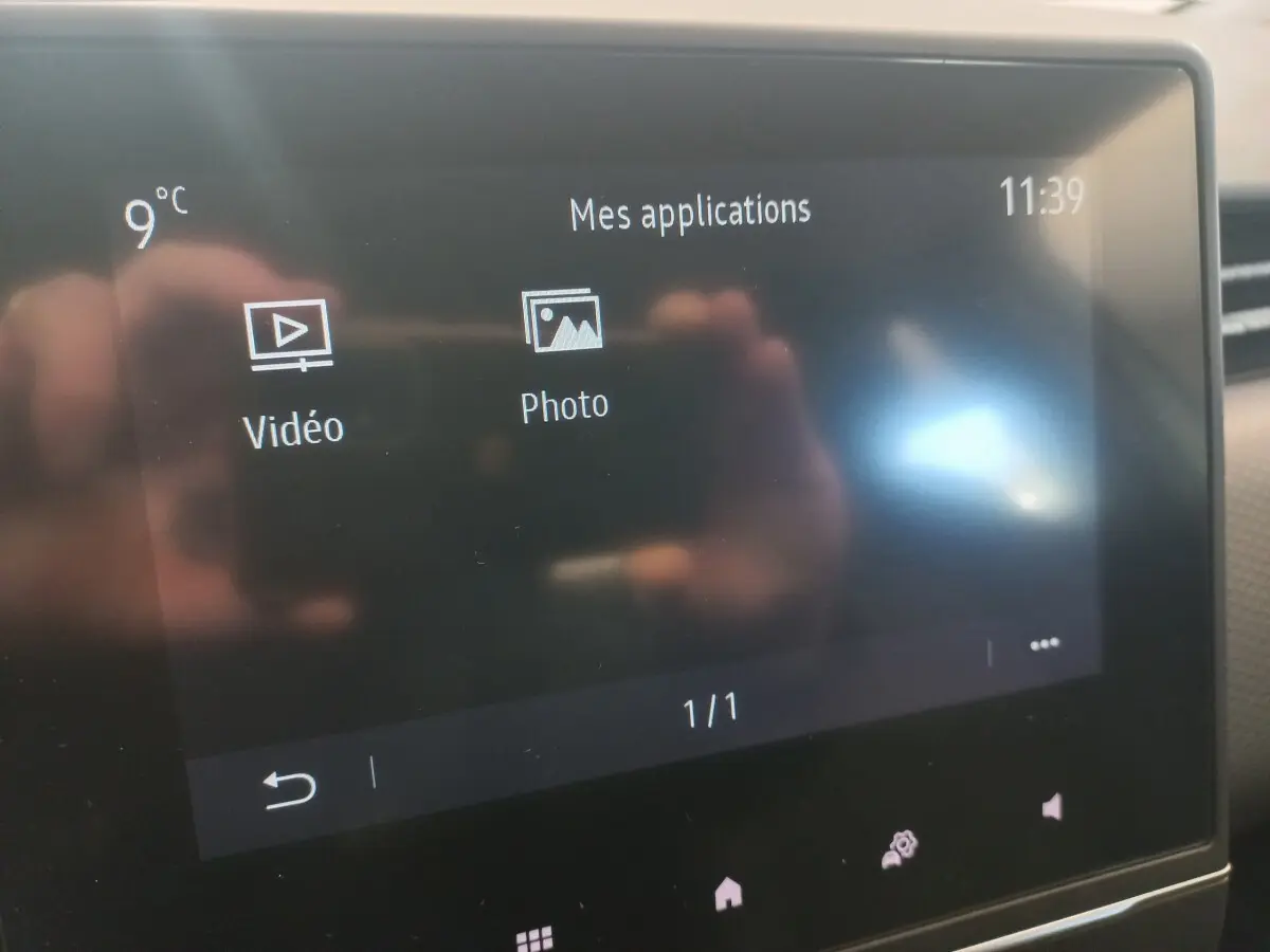 Écran tactile central de la Renault Clio Business blanc, affichant les applications vidéo et photo, température 9°C.