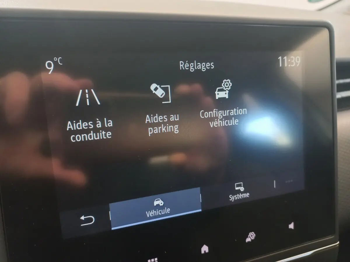 Écran tactile intérieur affichant les réglages d’aides à la conduite et parking dans une Renault Clio blanche.