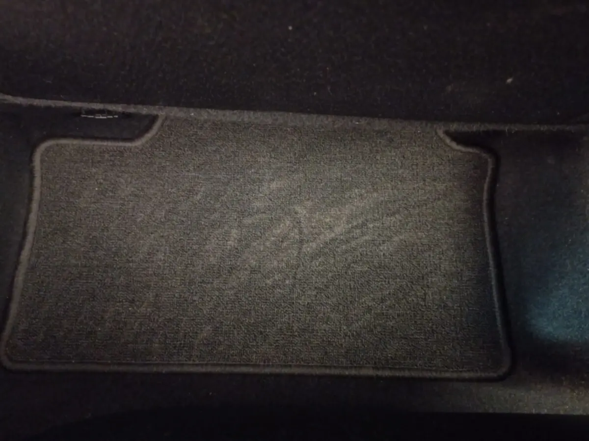 Tapis de sol noir en tissu dans l'habitacle d'une Renault Clio Business blanche, vue intérieure au sol côté passager.