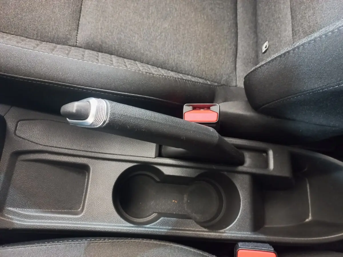 Vue rapprochée de la console centrale intérieure noire de la Renault Clio Business avec frein à main manuel et porte-gobelets.