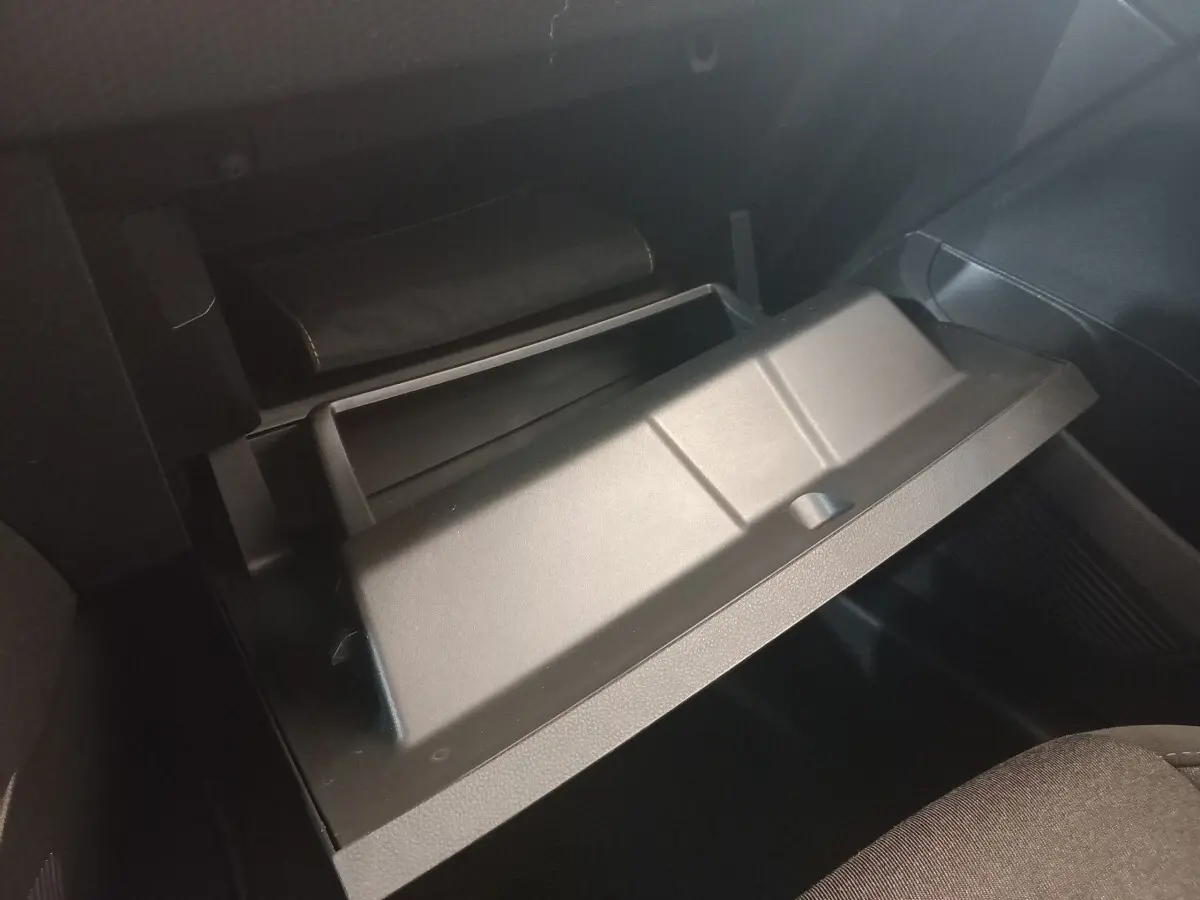 Gant de boîte à gants ouvert en plastique noir dans l'habitacle d'une Renault Clio Business blanche, vue côté passager.