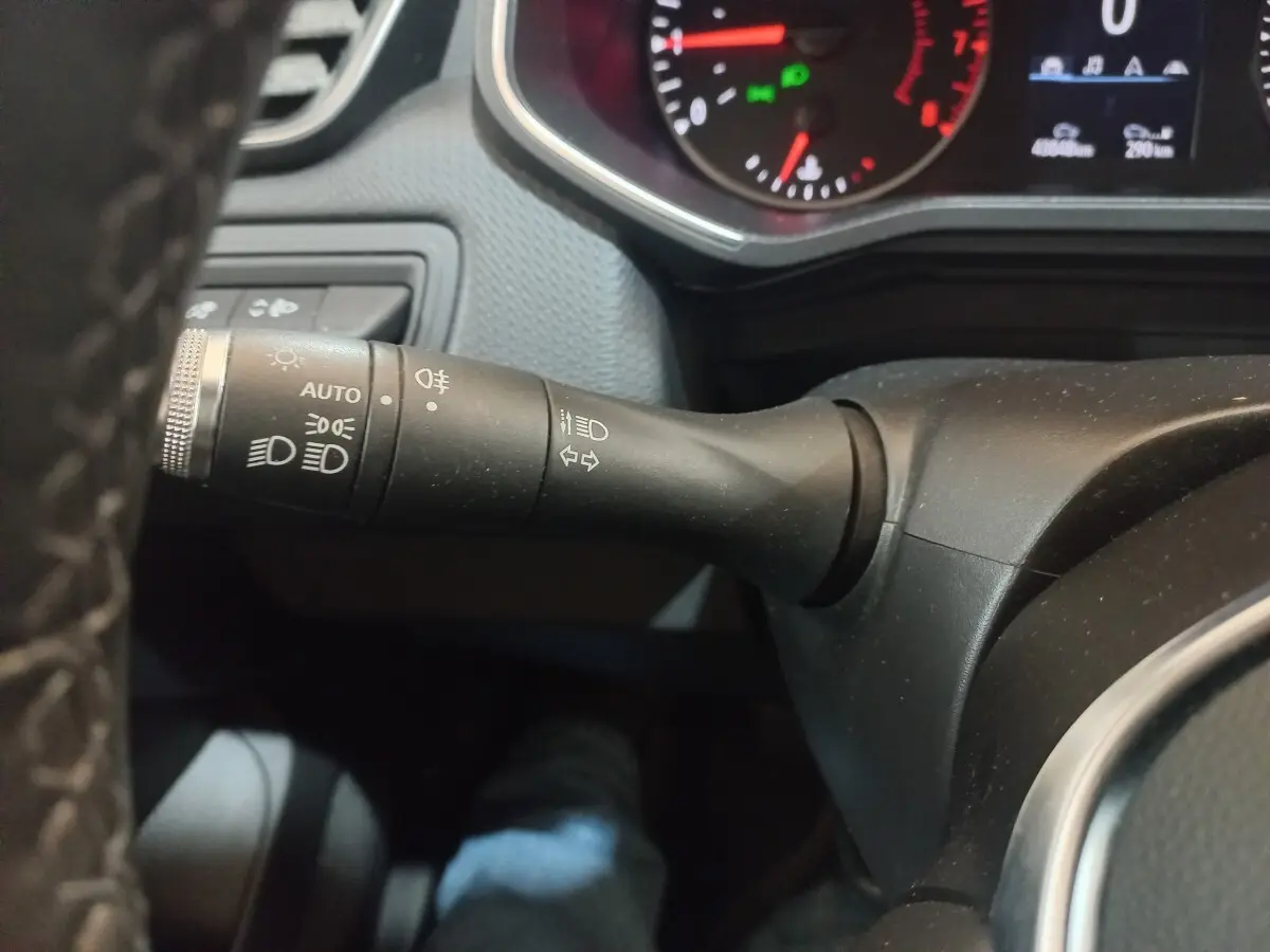 Gros plan sur la commande des phares et clignotants à gauche du volant dans le tableau de bord d'une Renault Clio blanche 2021.