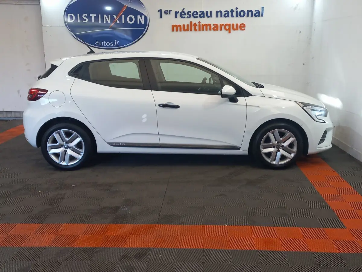 Profil côté gauche d'une Renault Clio Business blanche de 2021, avec jantes alliage et feux arrière LED visibles.