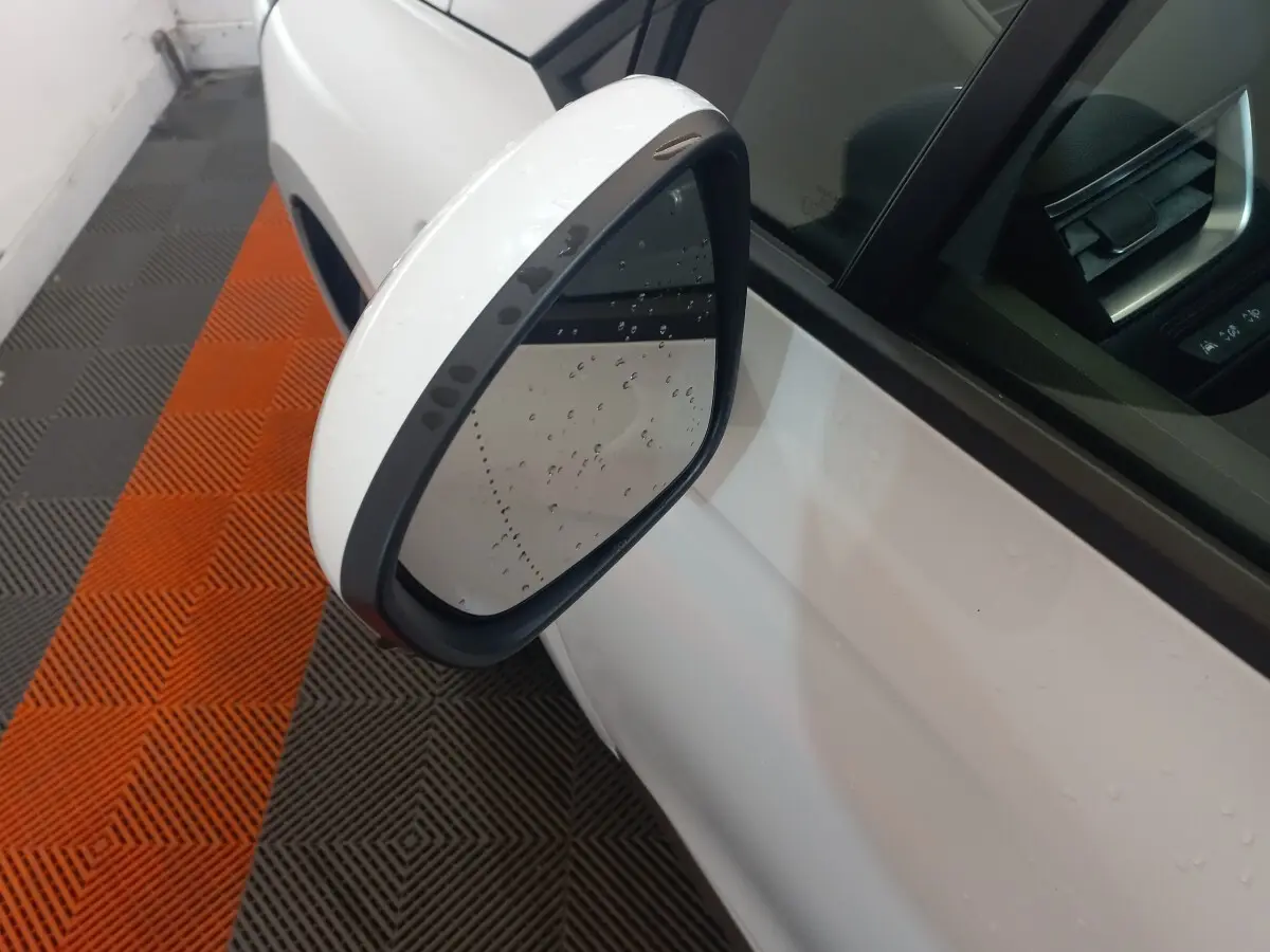 Rétroviseur extérieur gauche blanc de Renault Clio Business 2021 avec gouttes d'eau, vue rapprochée en intérieur.
