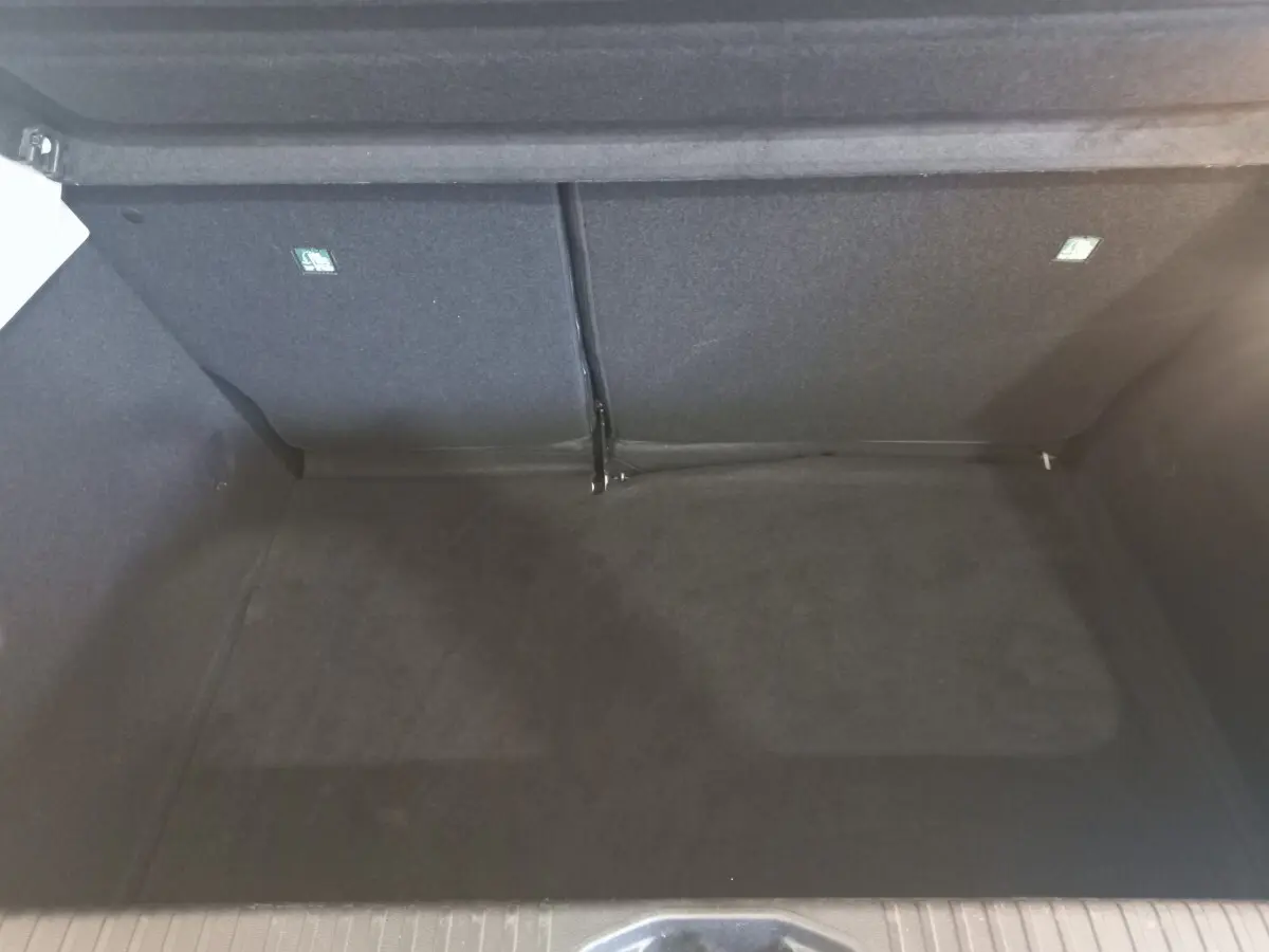 Vue intérieure du coffre spacieux et vide de la Renault Clio Business blanche, version 2021, avec banquette arrière rabattue.