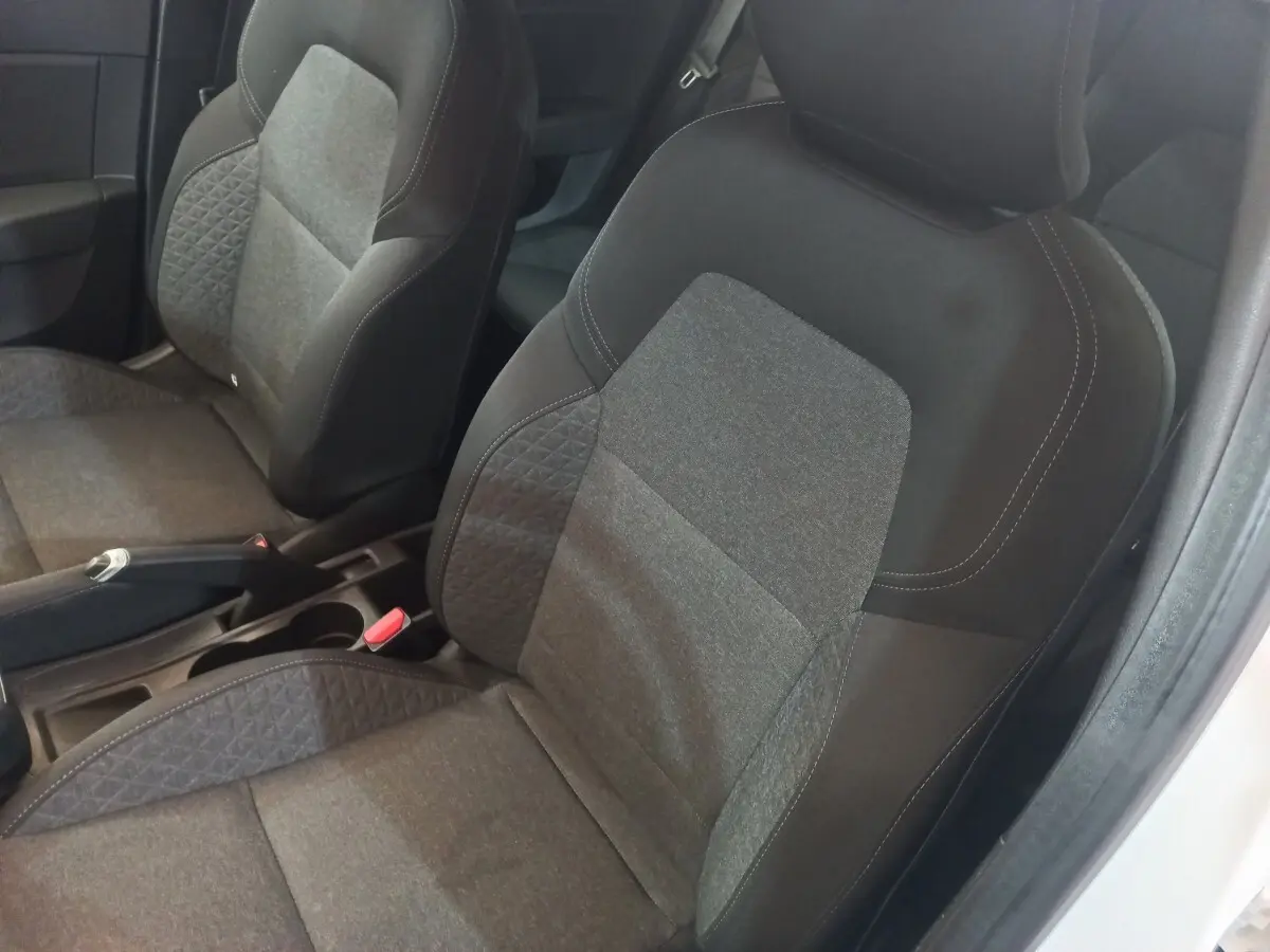 Vue rapprochée des sièges avant gris foncé et tissu de la Renault Clio Business SCe 65 blanche, intérieur sobre.