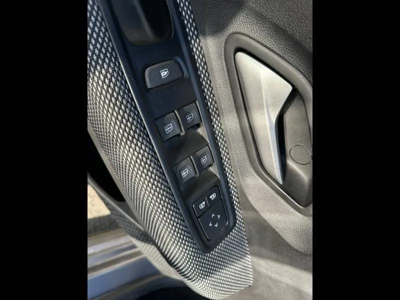 Gros plan sur la commande des vitres et le bouton de réglage des rétroviseurs côté conducteur du Dacia Jogger gris Schiste métallisé.