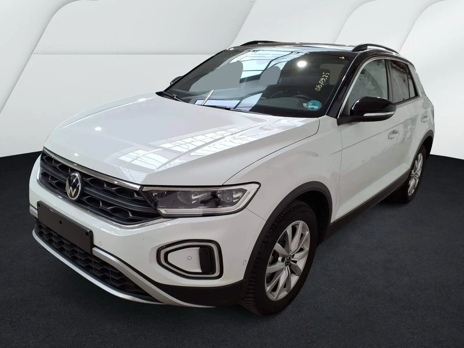 Volkswagen T-Roc blanc en 3/4 avant droit, avec toit noir et jantes alliage, sur fond neutre intérieur.
