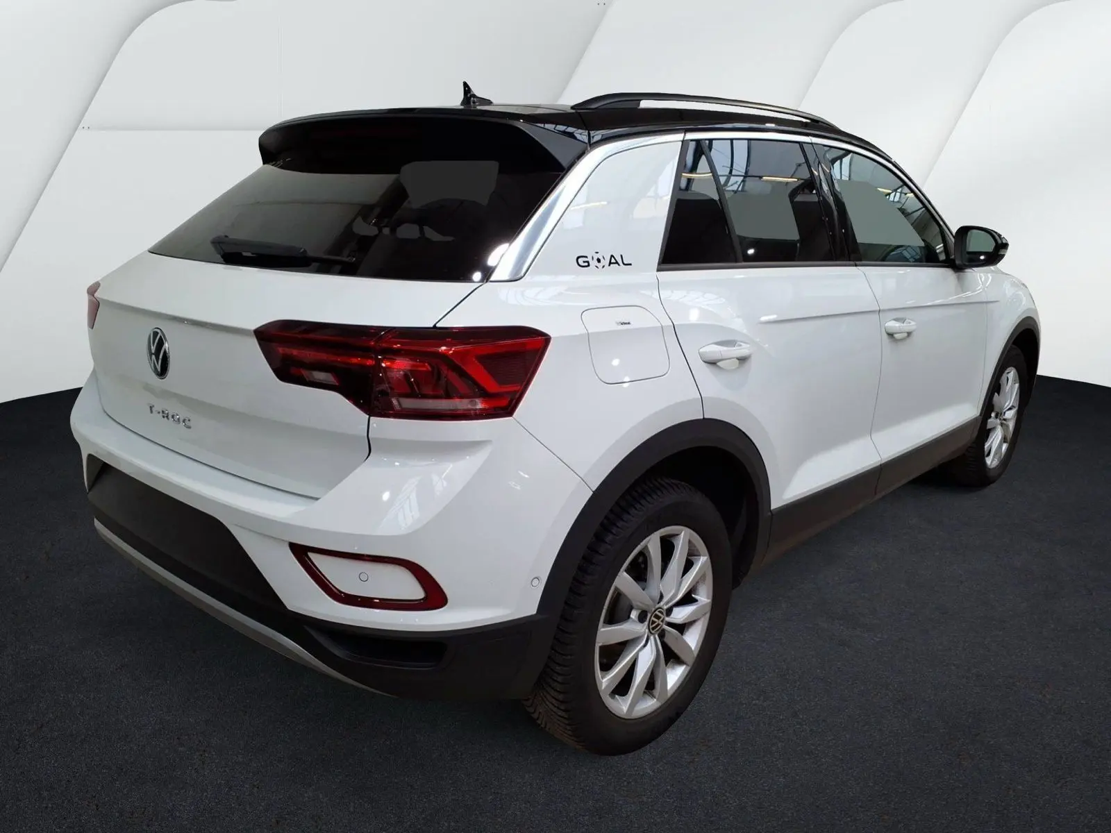 Volkswagen T-Roc blanc en 3/4 arrière droit, toit noir et badge Goal sur le montant arrière.