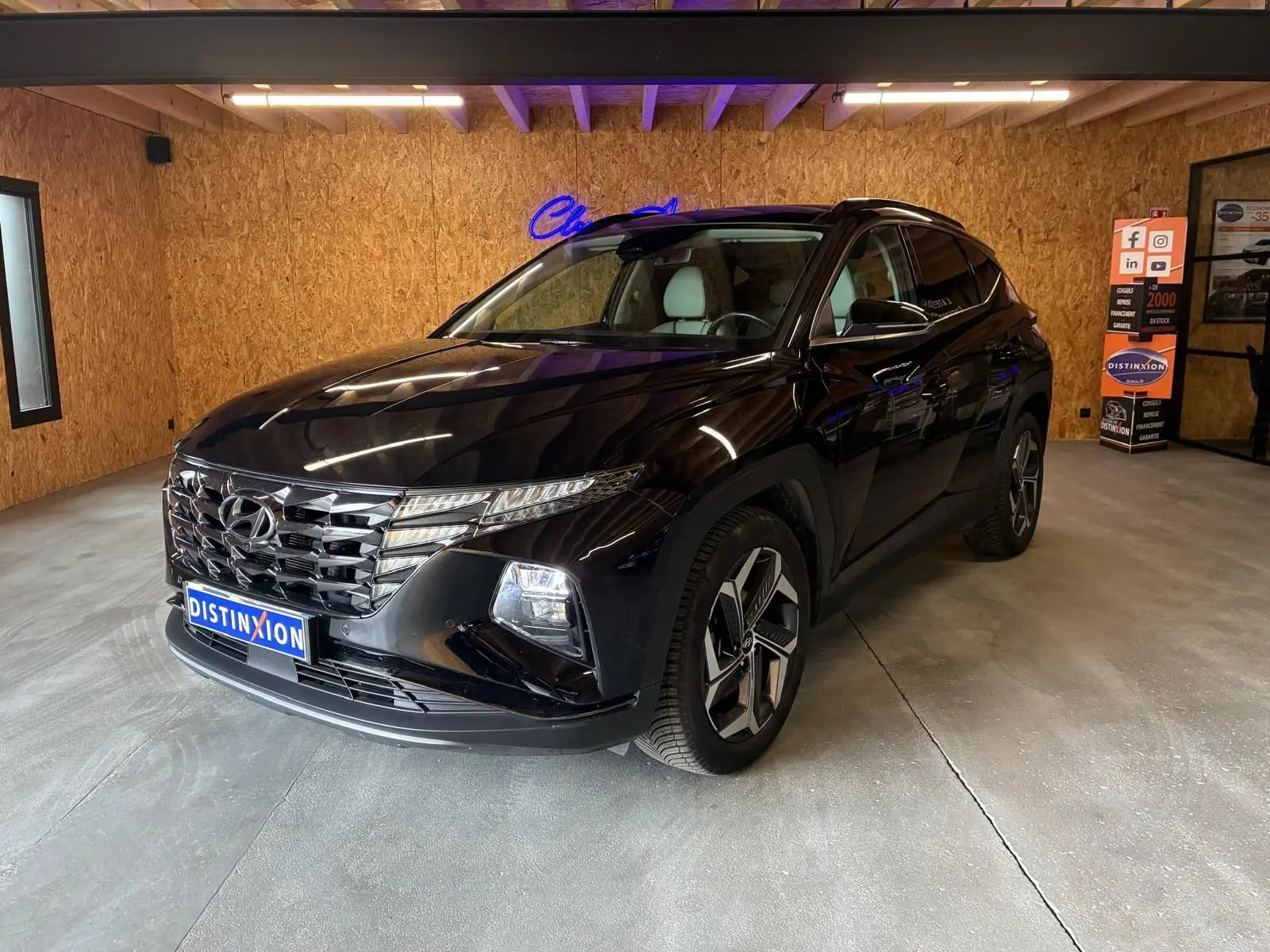 Hyundai Tucson noir 2022 en 3/4 avant droit, avec calandre distinctive et jantes modernes, dans un showroom intérieur.