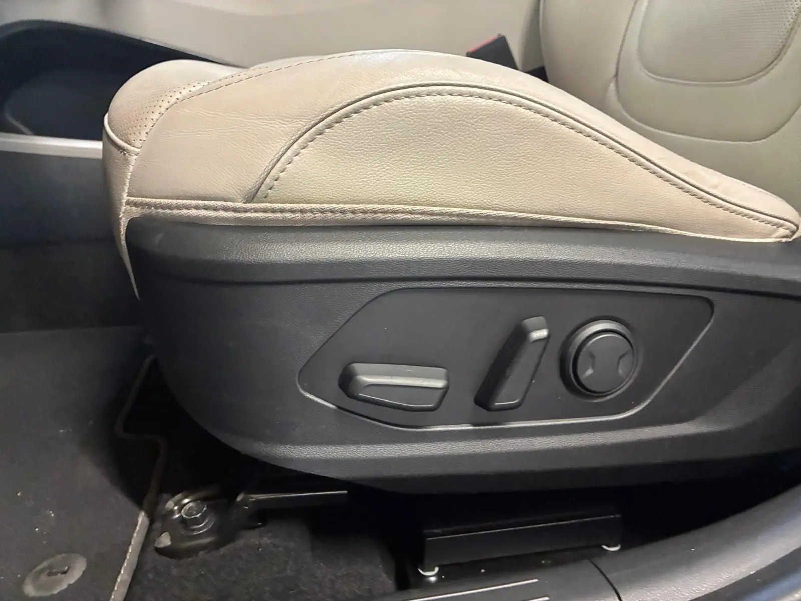 Gros plan sur les commandes électriques du siège beige côté conducteur du Hyundai Tucson 2022 hybride.