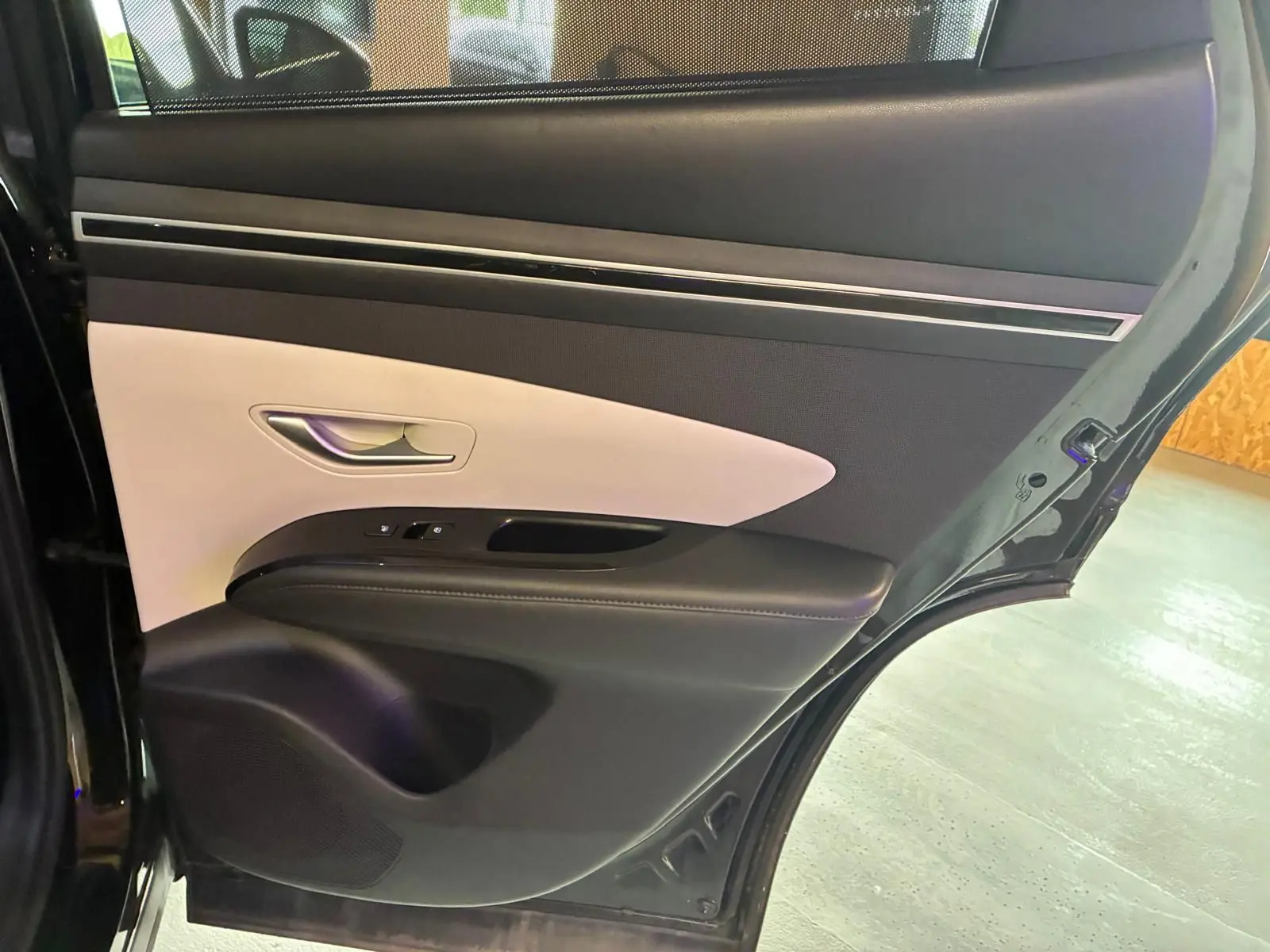 Vue rapprochée de la porte arrière gauche noire du Hyundai Tucson 2022 avec garniture intérieure bicolore beige et noire.