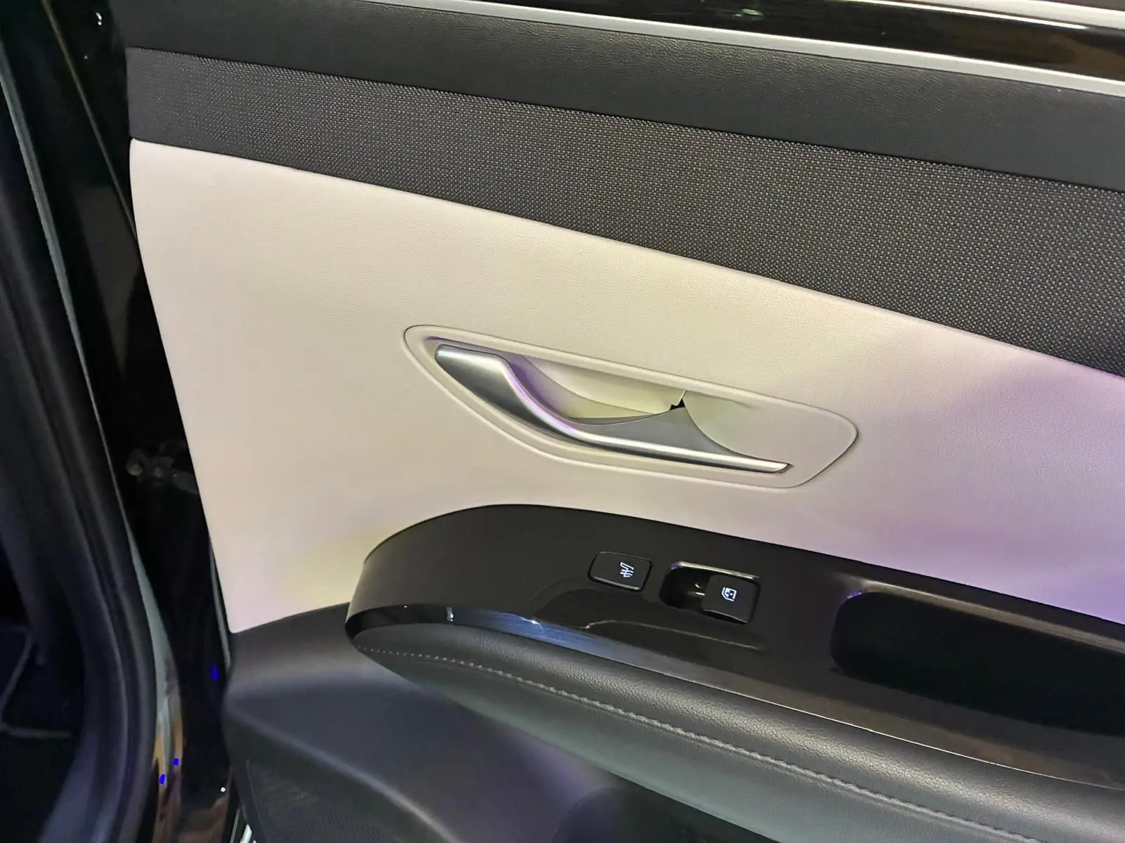 Détail de la porte avant gauche du Hyundai Tucson noir 2022, montrant la poignée argentée et les commandes électriques.