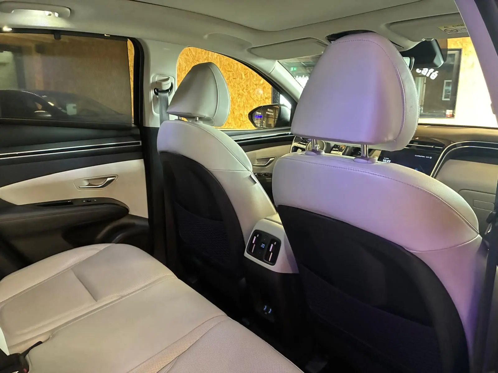 Vue intérieure arrière du Hyundai Tucson 2022, sièges en cuir beige avec détails noirs et commandes climatisation arrière.