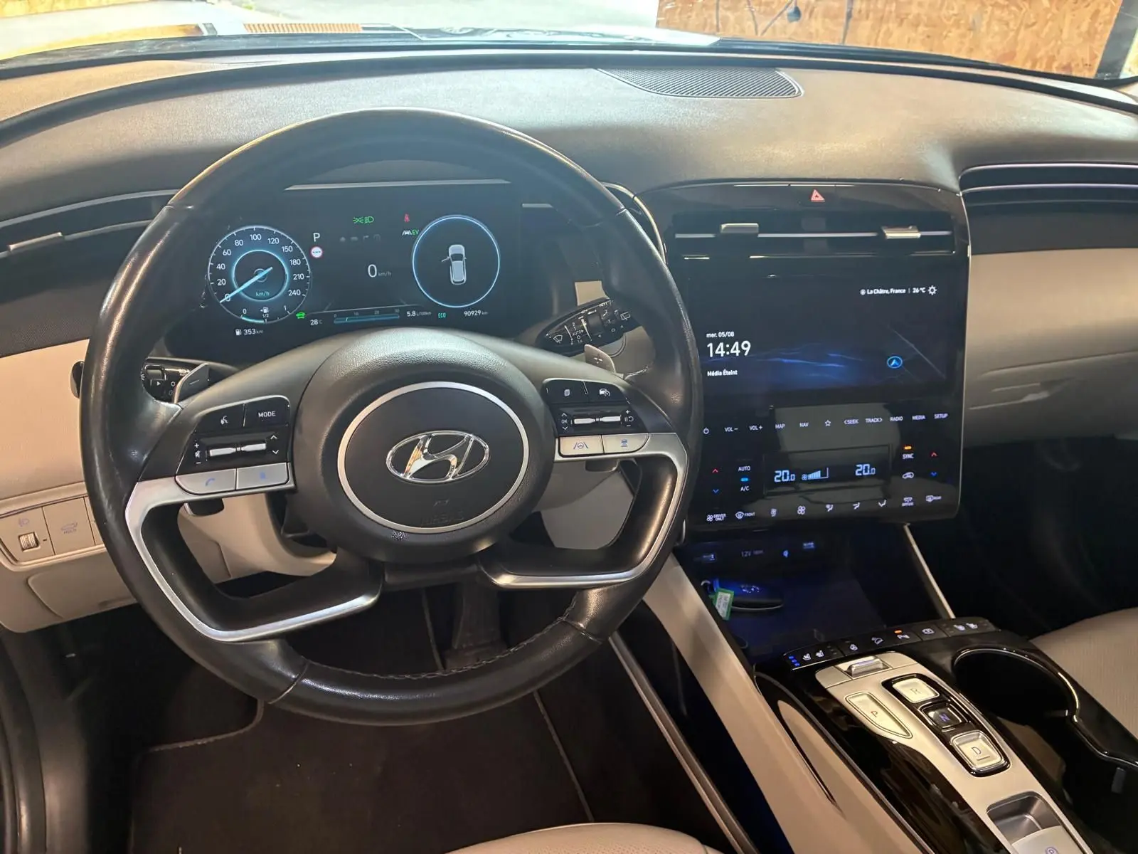 Vue intérieure centrée sur le volant noir et le tableau de bord numérique du Hyundai Tucson hybride 2022, avec écran tactile vertical.