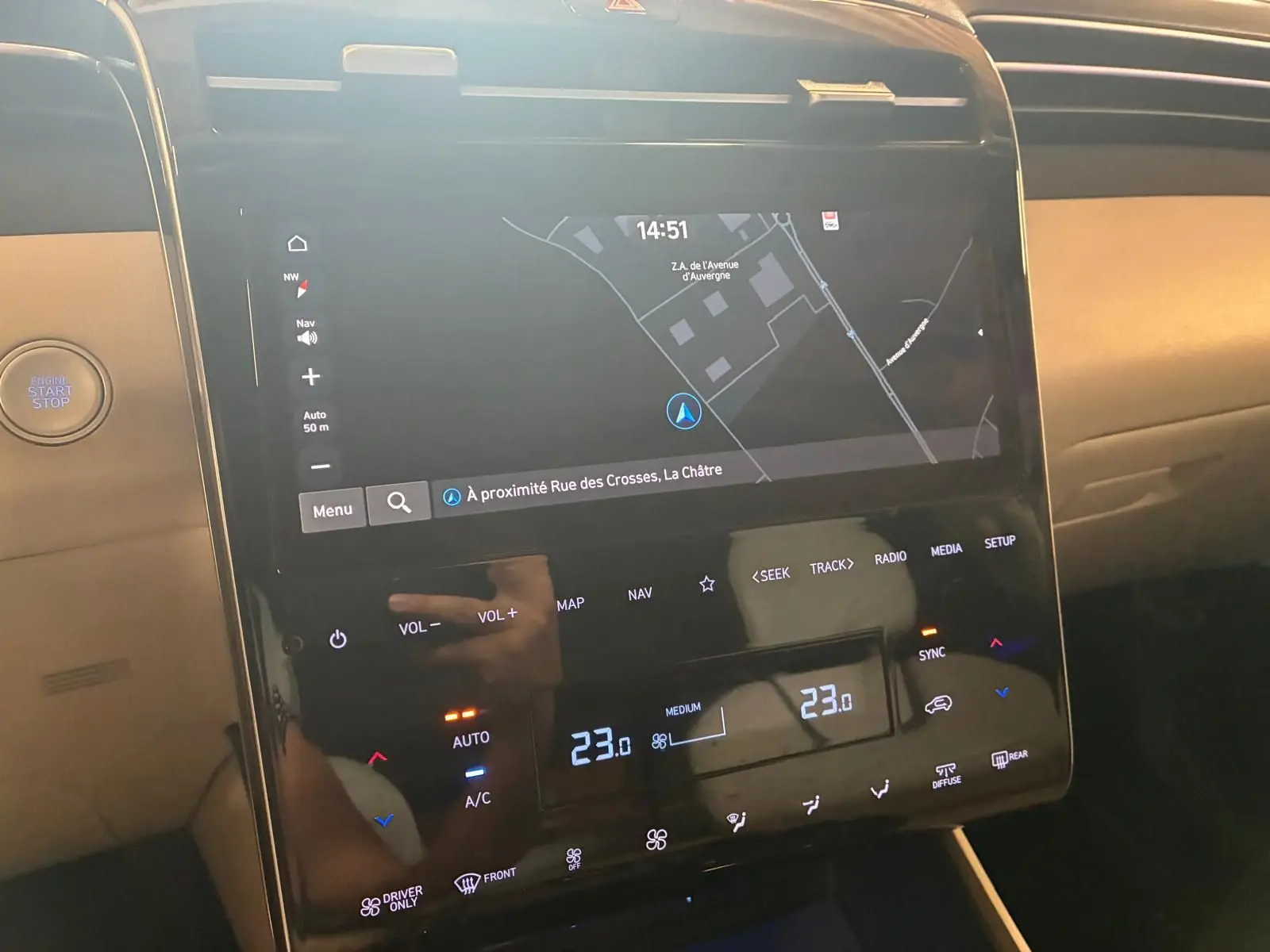 Vue rapprochée de la console centrale du Hyundai Tucson 2022 noire, affichant l'écran tactile du GPS et les commandes climatisation.
