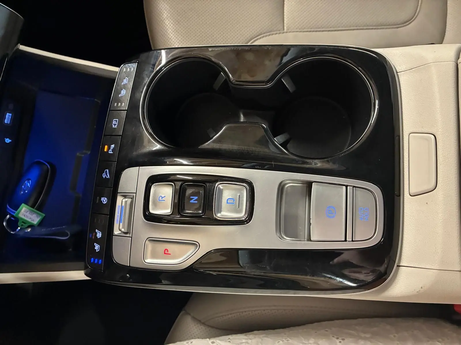 Vue rapprochée de la console centrale beige du Hyundai Tucson 2022, avec commandes de boîte auto et porte-gobelets noirs.