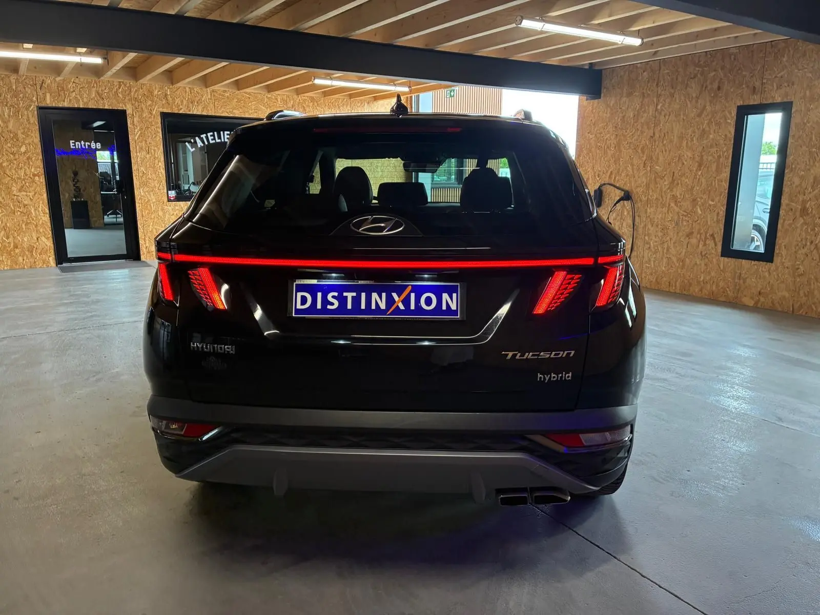 Vue arrière d'un Hyundai Tucson noir hybride 2022 avec feux arrière LED allumés dans un garage.