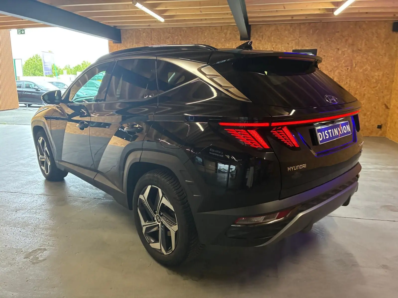 Vue 3/4 arrière droite du Hyundai Tucson noir 2022 hybride, avec feux arrière LED et jantes alliage distinctives.