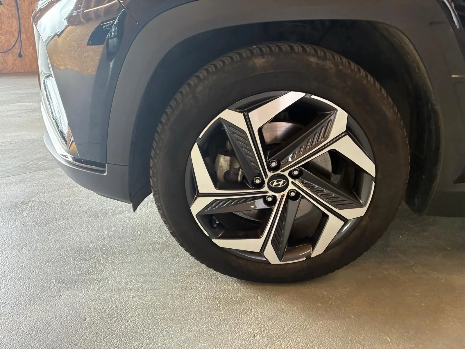 Gros plan sur la roue avant droite noire du Hyundai Tucson 2022 avec jante alliage bicolore au design moderne.
