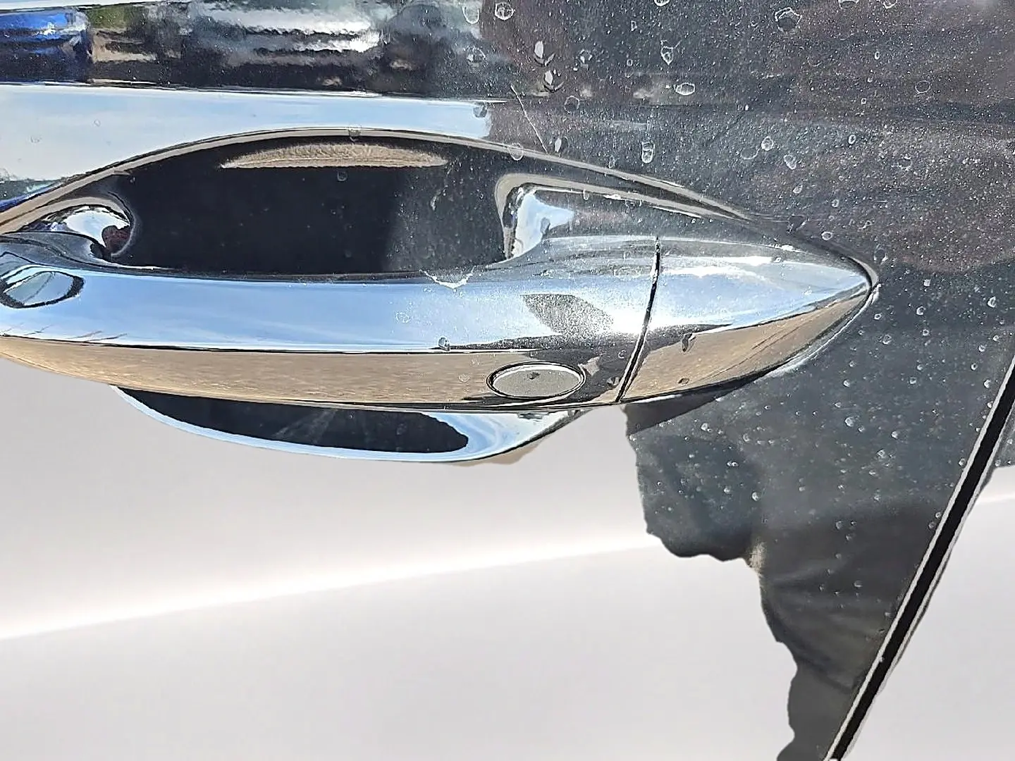 Poignée de porte chromée en gros plan sur la portière noire du Hyundai Tucson 2026 hybride.
