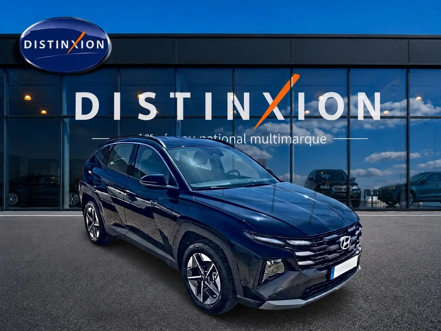 Vue 3/4 avant du Hyundai Tucson noir 2026 devant une vitrine avec logo Distinxion, jantes alu et phares LED visibles.
