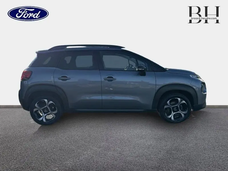 Profil droit d'un Citroën C3 Aircross gris acier avec barres de toit et jantes diamantées 17 pouces.