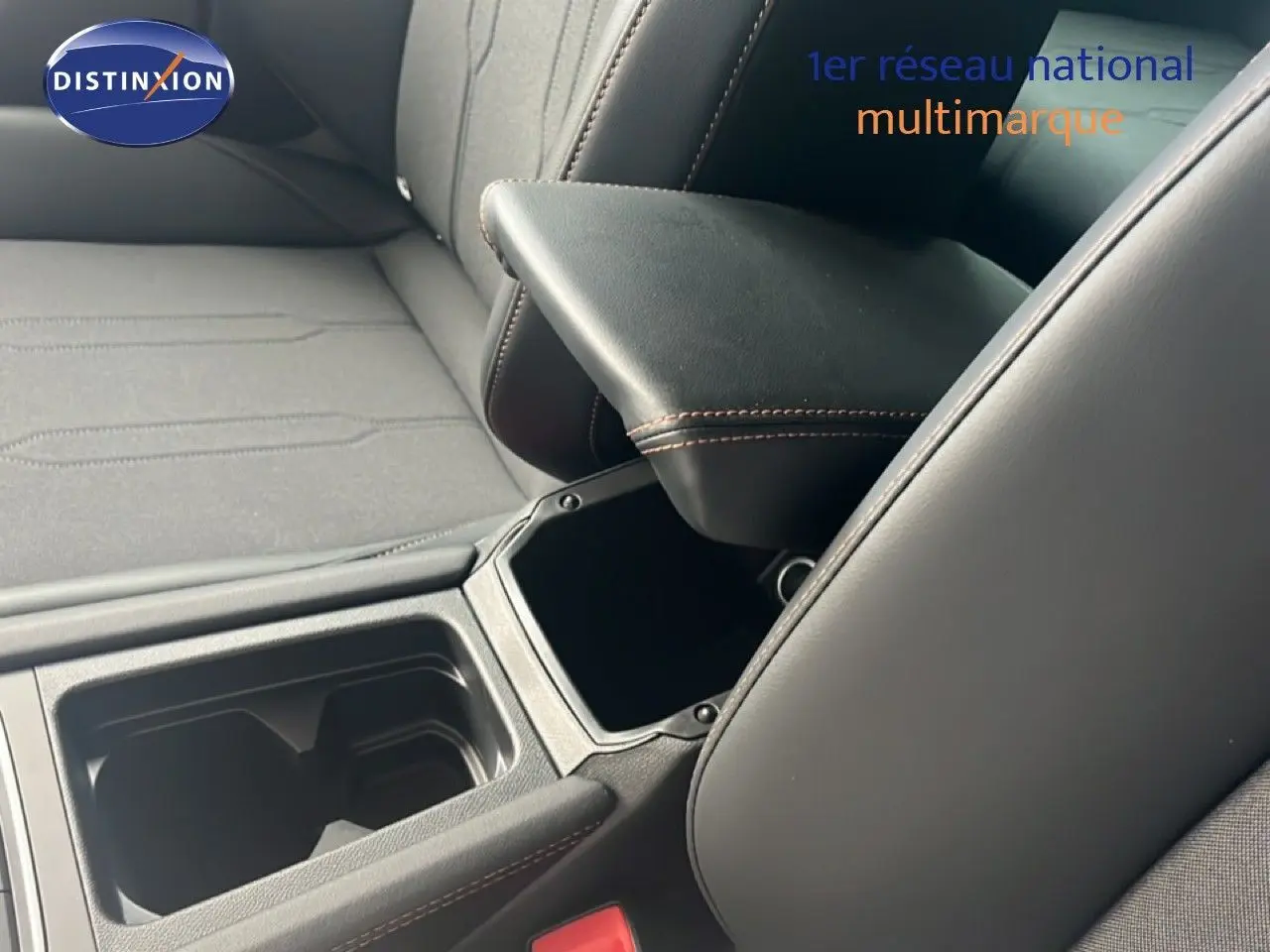 Détail intérieur montrant l'accoudoir central noir avec surpiqûres marron et les sièges tissu cuir du CUPRA Formentor bleu Fjord 2026.