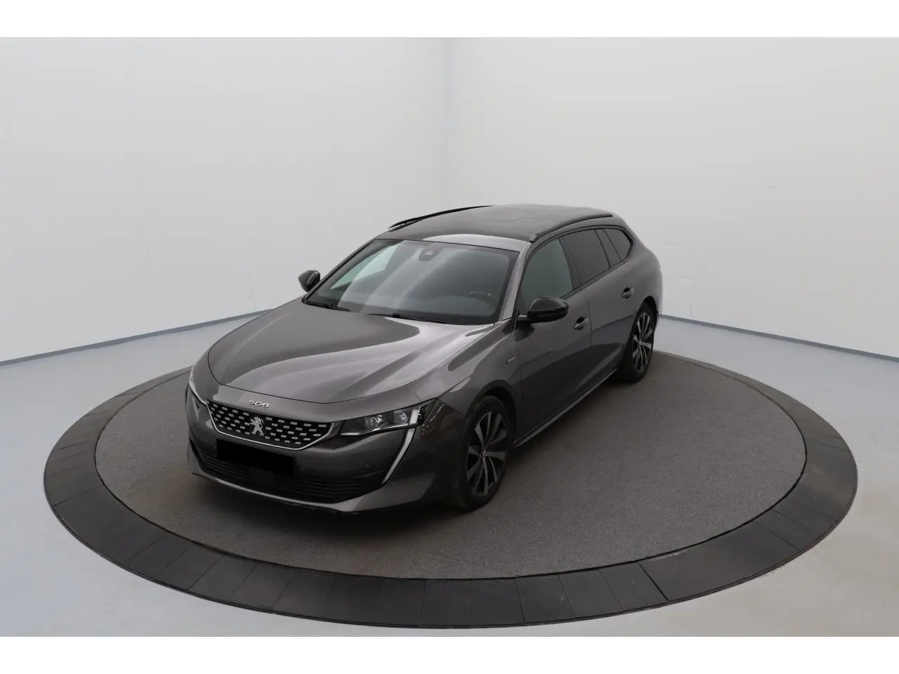 Peugeot 508 SW gris Platinium vue 3/4 avant droit, avec jantes bi-ton et toit panoramique noir brillant.