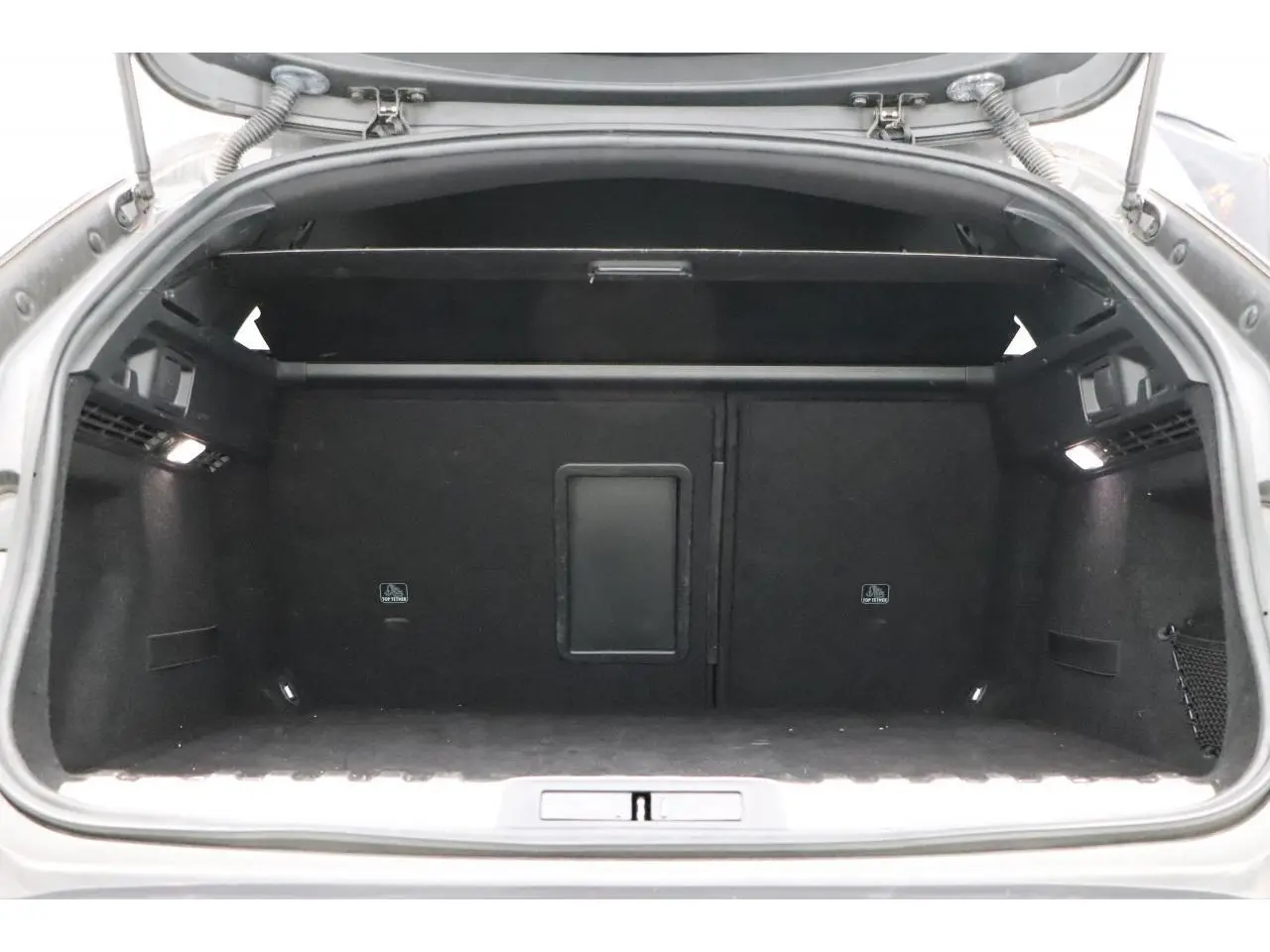 Coffre ouvert de la Peugeot 508 SW gris Platinium, vue intérieure arrière montrant l'espace de chargement noir.