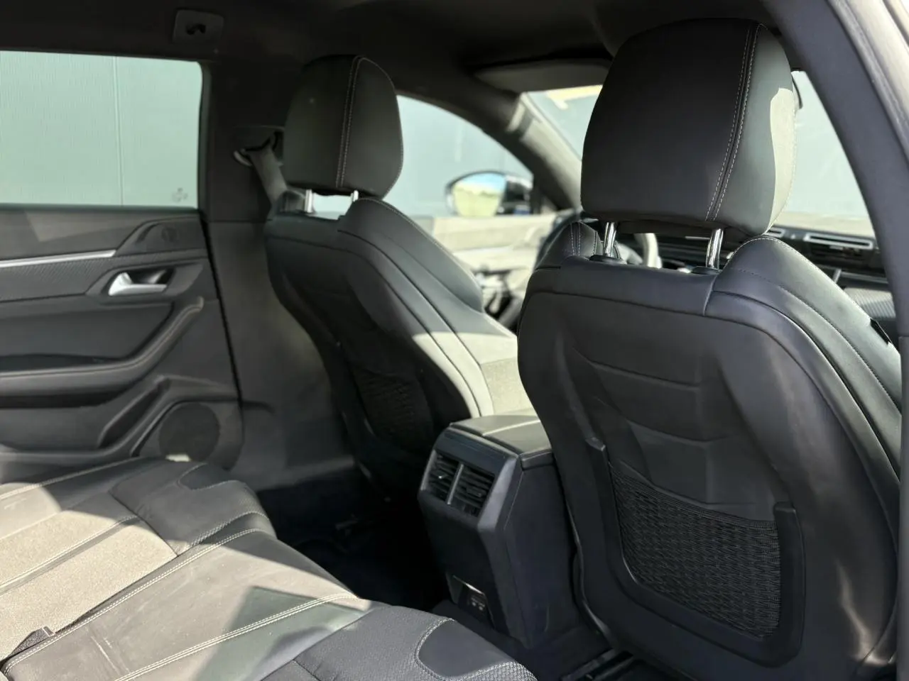 Vue arrière de l'habitacle noir de la Peugeot 508 SW GT Line 2020, mettant en valeur les sièges avant et aérateurs centraux.