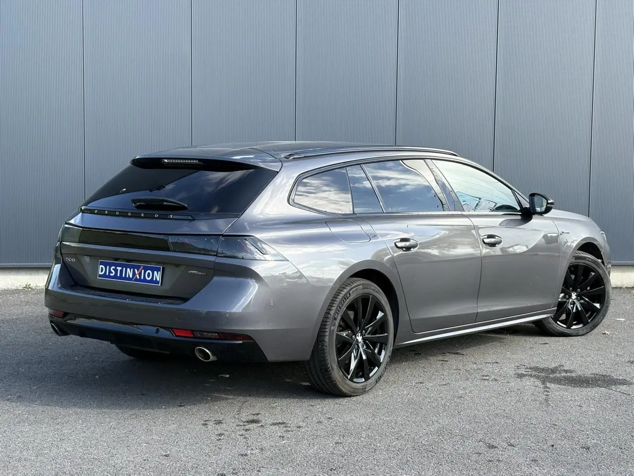 Peugeot 508 SW gris Platinium vue 3/4 arrière droit avec jantes noires et vitres surteintées.