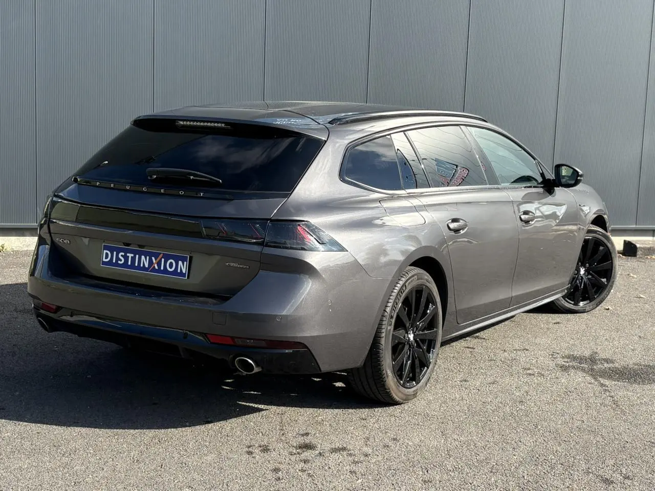 Peugeot 508 SW gris Platinium vue 3/4 arrière droit avec jantes noires et vitres surteintées.