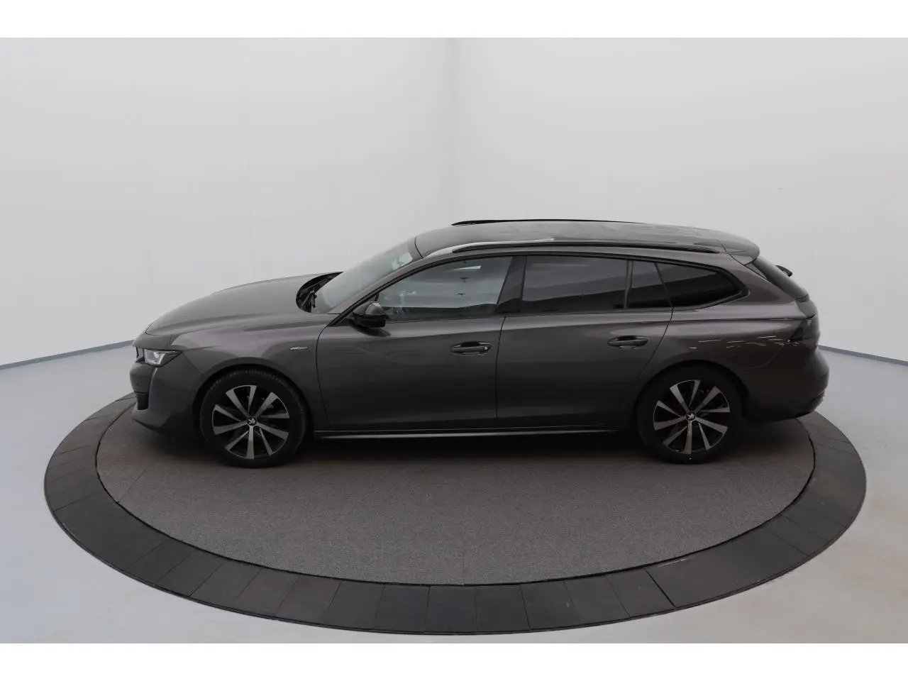 Peugeot 508 SW gris Platinium vue de profil côté gauche, jantes alliage bi-ton et barres de toit noires brillantes.