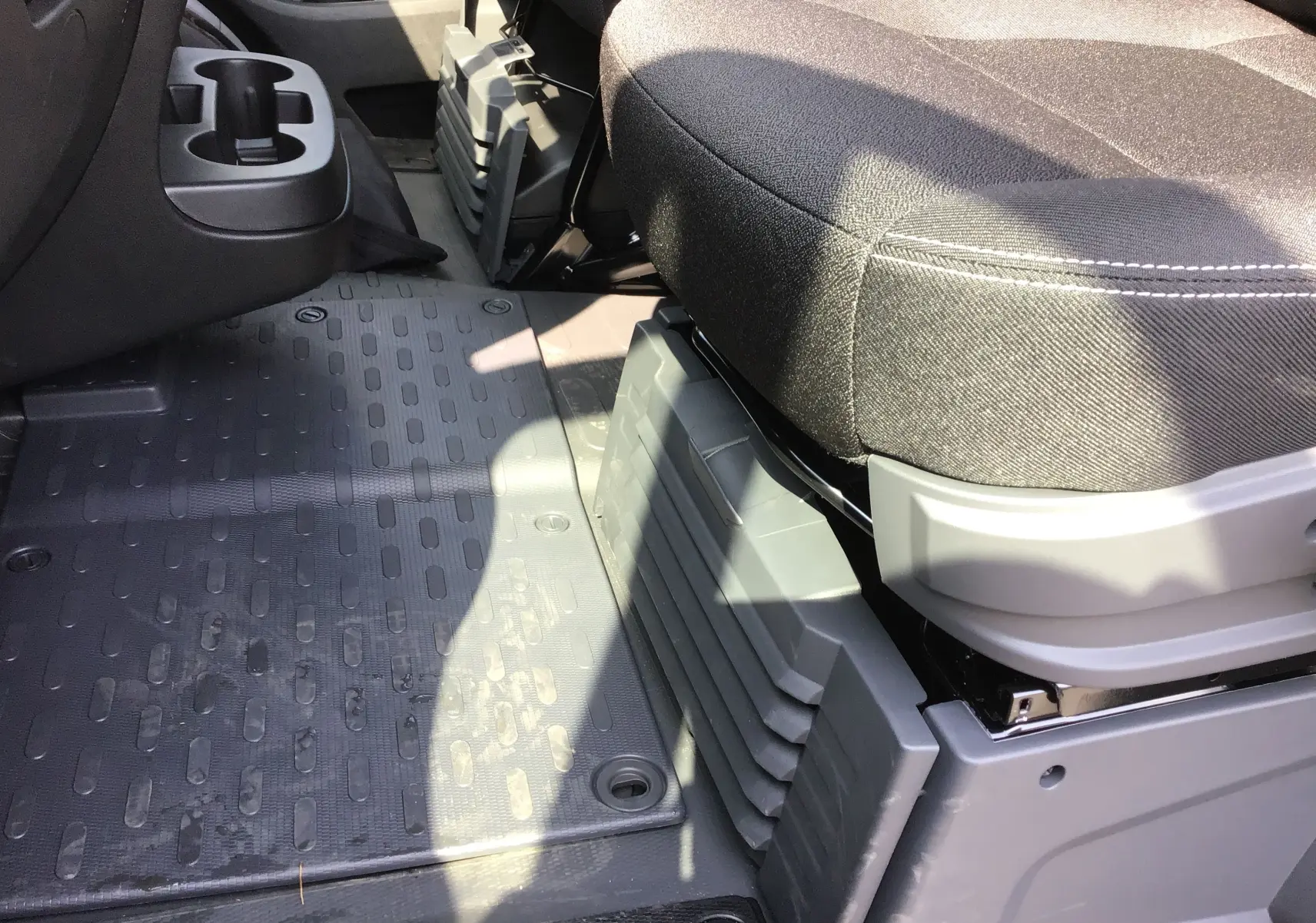 Gros plan sur l'espace au sol côté passager du Peugeot Boxer Fourgon gris Artense, montrant le siège avant et le tapis caoutchouc.