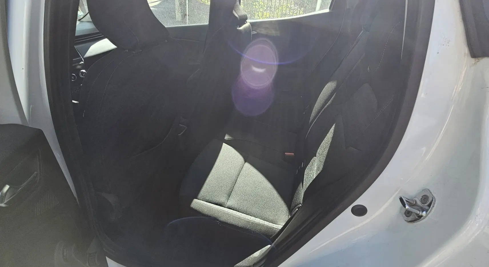 Vue intérieure côté arrière droit de la Renault Clio blanche glacier 2021, sièges arrière en tissu noir et ouvertures de porte visibles.