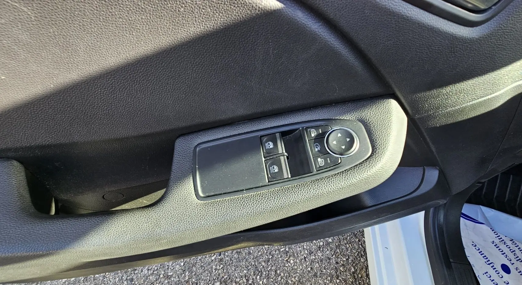 Gros plan sur la commande des vitres électriques côté conducteur de la Renault Clio blanc glacier 2021.