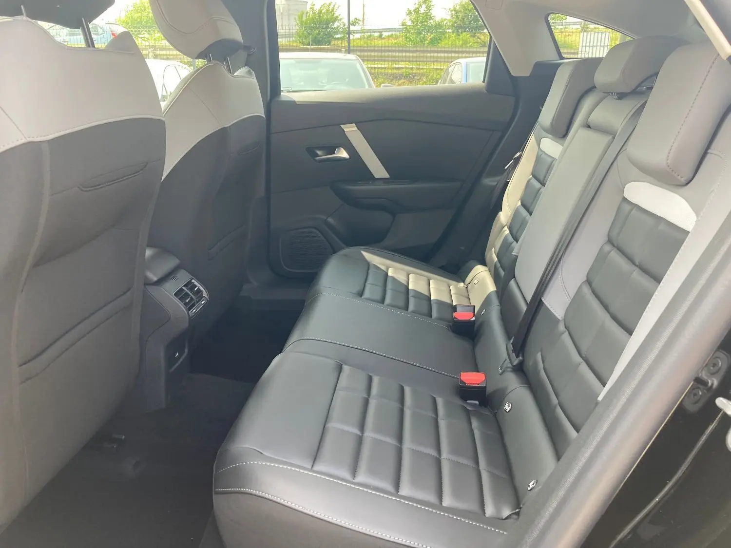Vue intérieure arrière droite de la Citroën C4 2025, sièges cuir TEP noir et gris avec surpiqûres blanches.