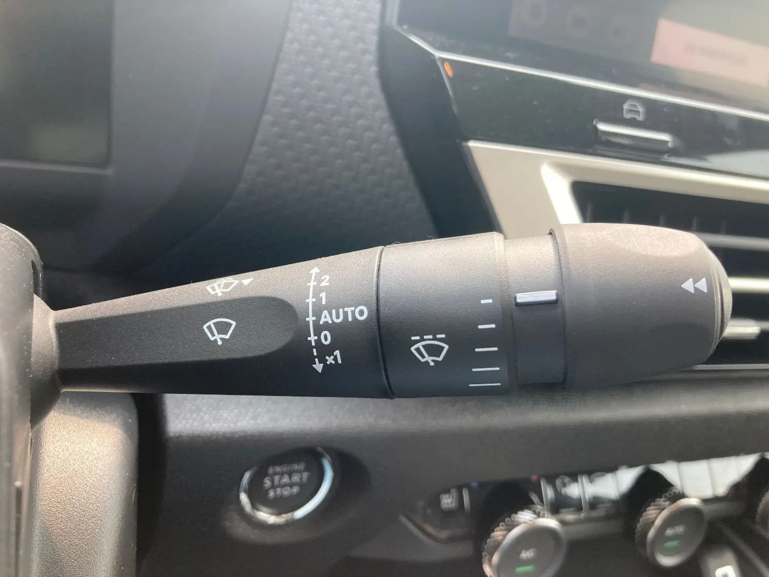 Gros plan sur la commande d'essuie-glace à gauche du volant dans l'habitacle noir de la Citroën C4 Facelift Hybrid 2025.