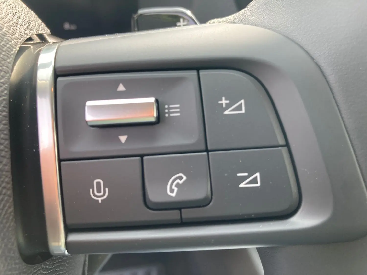 Gros plan sur les commandes au volant du Citroën C4 noir Perla, boutons de volume et téléphone visibles.