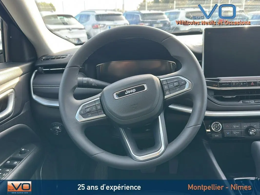 Vue intérieure centrée sur le volant du Jeep Compass noir 2024 avec tableau de bord et écran tactile visible.
