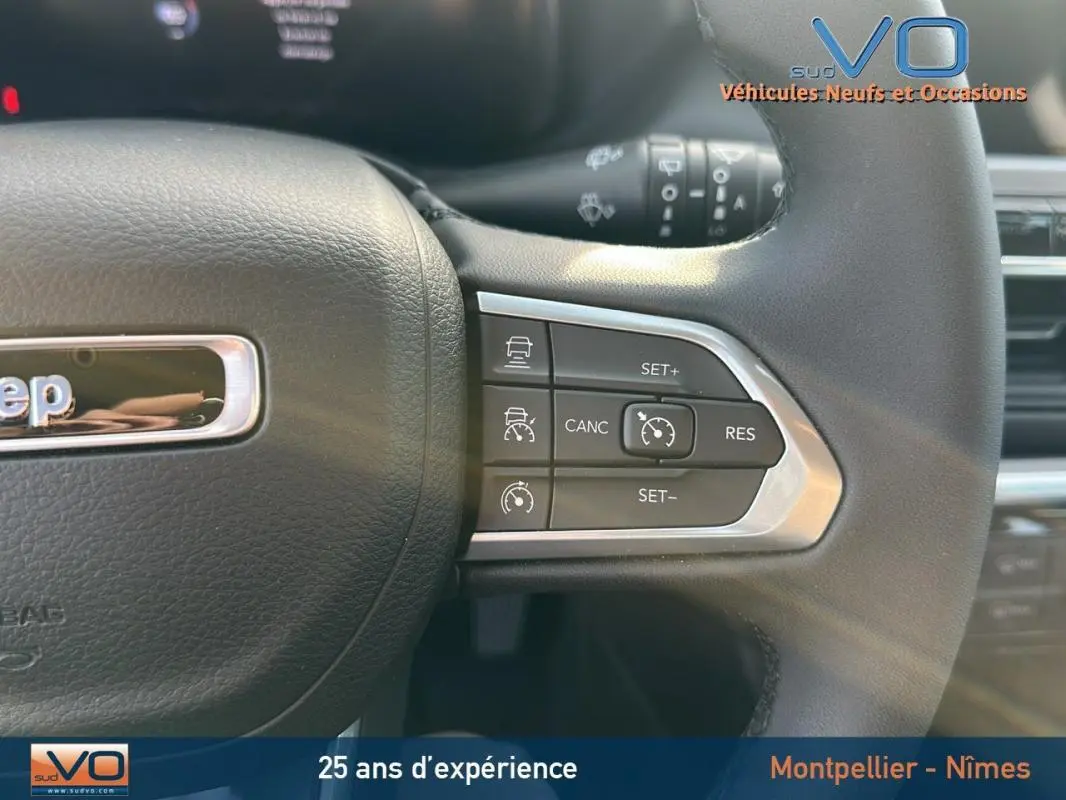 Gros plan sur le volant noir du Jeep Compass 2024 montrant les commandes du régulateur de vitesse à droite.