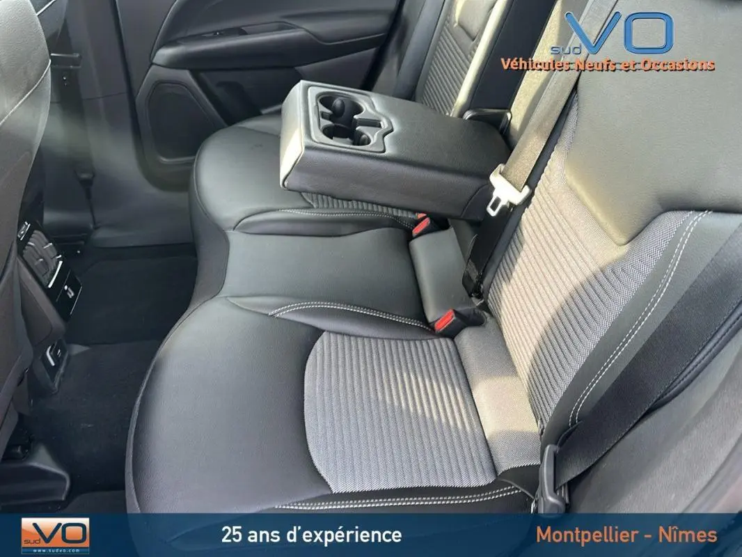 Vue intérieure des sièges arrière noirs du Jeep Compass 2024 avec accoudoir central relevé et ceintures visibles.